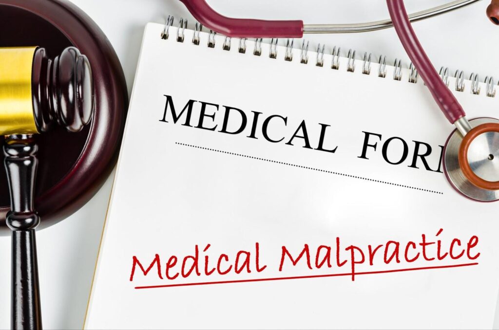 Medical malpractice form on white tabletop with stethoscope and gavel